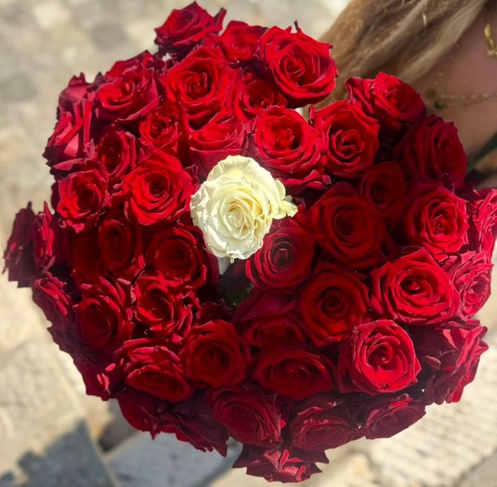 Round bouquet of red roses with a white focal bloom.