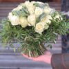 a hand holding a bouquet of white roses