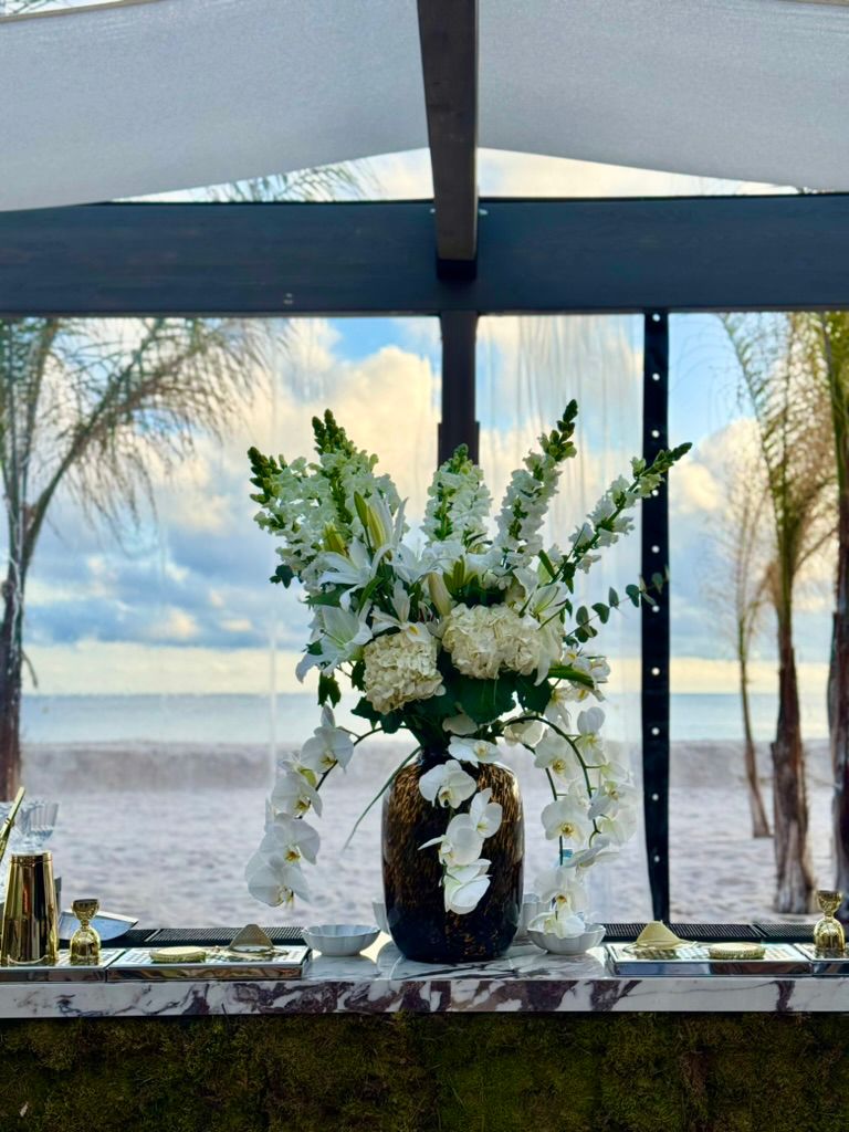 White ceremony flowers by the sea with elegant roses and lilies.