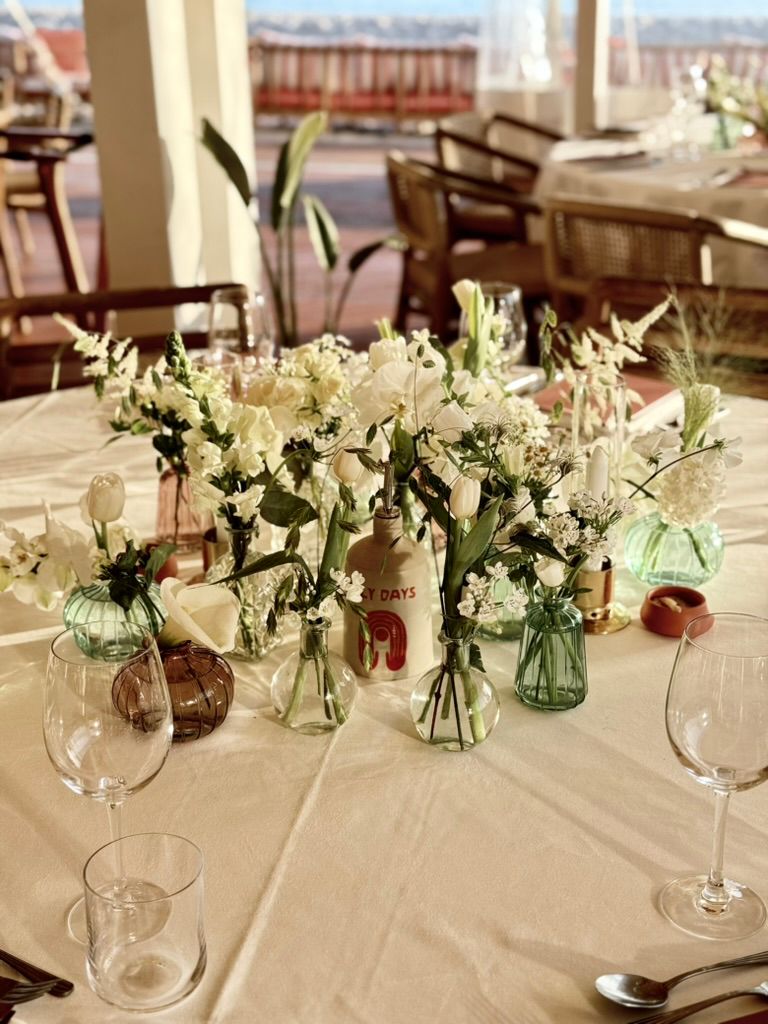 White floral table centerpieces with candles and glass vases.